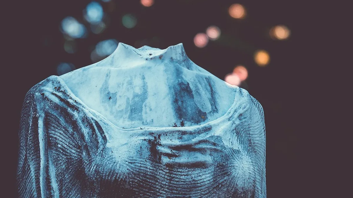 The upper torso of a long-sleeved, high-necked garment with a textured surface, featuring a collar and a small hole at the top of the neck.