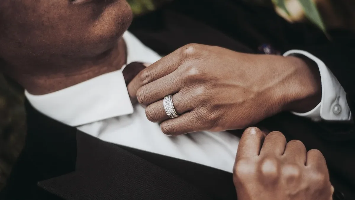 A man in a suit having his collar adjusted by another person.